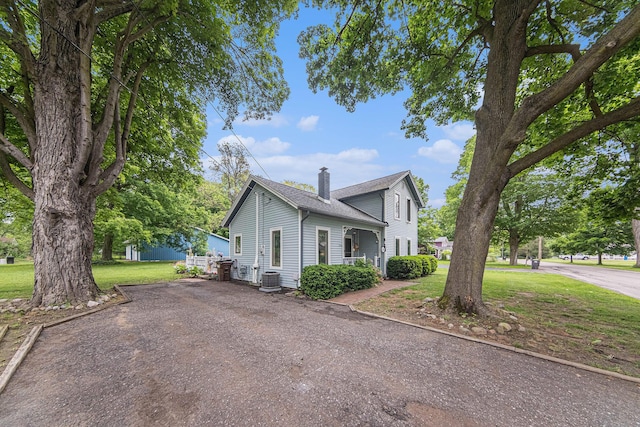 436 Portage St, Grass Lake, MI 49240 - traditional-style house with a chimney, a shingled roof, a front yard, driveway, and central air condition unit