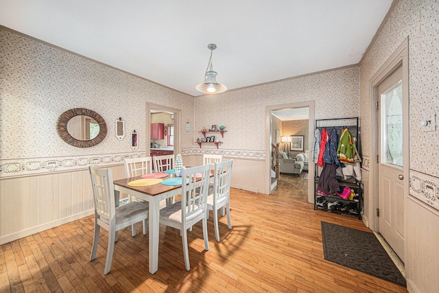 436 Portage St, Grass Lake, MI 49240 - dining area featuring wallpapered walls, a wainscoted wall, light wood-type flooring, and crown molding