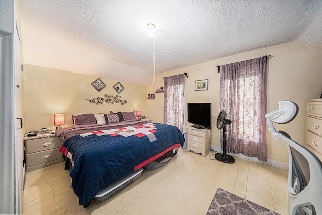 436 Portage St, Grass Lake, MI 49240 - bedroom with vaulted ceiling, a textured ceiling, light wood-style flooring, and baseboards