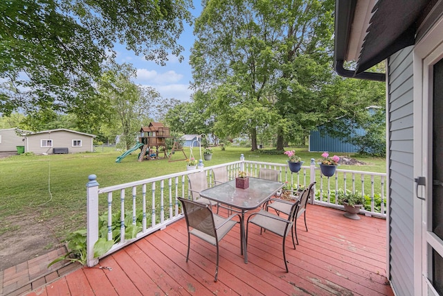 436 Portage St, Grass Lake, MI 49240 - wooden terrace with outdoor dining area, a lawn, a playground, and an outbuilding
