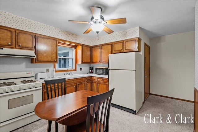 787 Andover St SE Unit 7, Grand Rapids, MI 49548 - kitchen featuring white appliances, under cabinet range hood, a sink, brown cabinetry, and light colored carpet