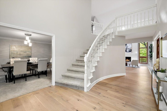 3427 E Dobson Pl, Ann Arbor, MI 48105 - stairs with wood finished floors, a warm lit fireplace, a towering ceiling, and ornamental molding