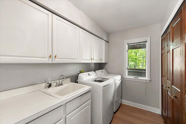 3427 E Dobson Pl, Ann Arbor, MI 48105 - laundry room with cabinet space, washing machine and dryer, light wood finished floors, and baseboards