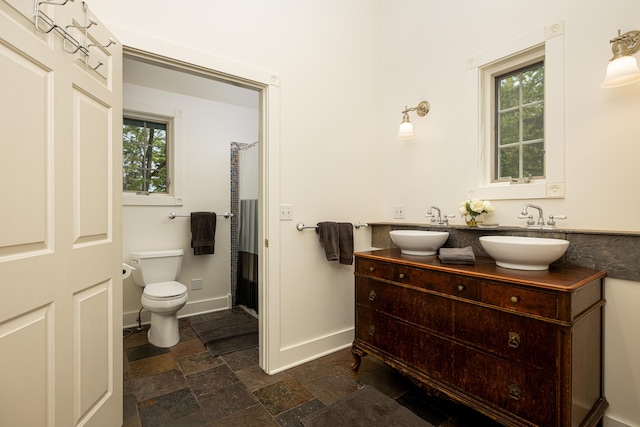818 S 7th St, Ann Arbor, MI 48103 - bathroom with stone finish flooring, double vanity, toilet, baseboards, and curtained shower
