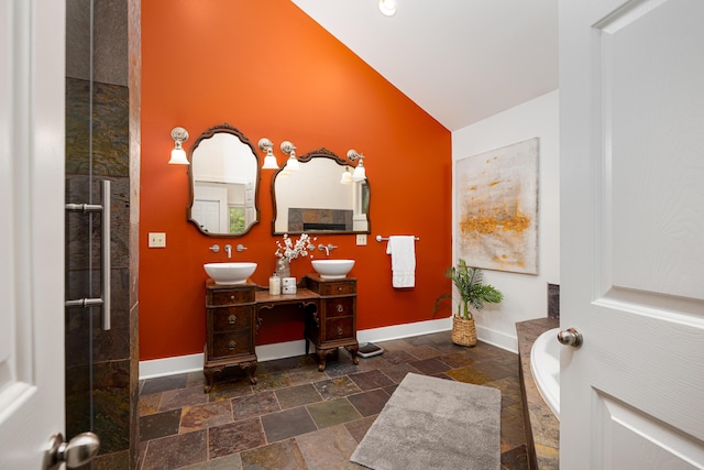 818 S 7th St, Ann Arbor, MI 48103 - bathroom with stone tile flooring, baseboards, double vanity, a relaxing tiled tub, and high vaulted ceiling
