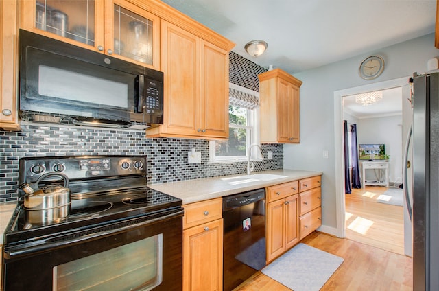 533 Beech St, East Lansing, MI 48823 - kitchen with black appliances, a sink, light countertops, light wood-type flooring, and backsplash