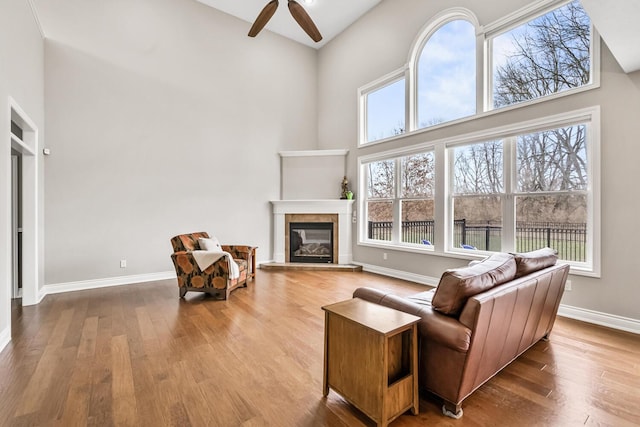 10693 Bear Lake Trl, Portage, MI 49024 - living area with a towering ceiling, wood finished floors, a fireplace, ceiling fan, and baseboards