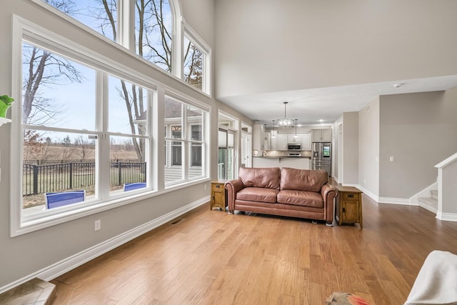 10693 Bear Lake Trl, Portage, MI 49024 - living area with light wood finished floors, baseboards, stairs, a chandelier, and a high ceiling