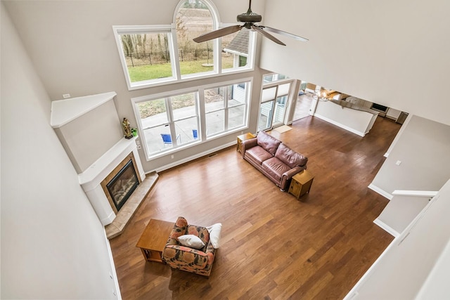 10693 Bear Lake Trl, Portage, MI 49024 - living area featuring a tile fireplace, a ceiling fan, wood finished floors, a high ceiling, and baseboards