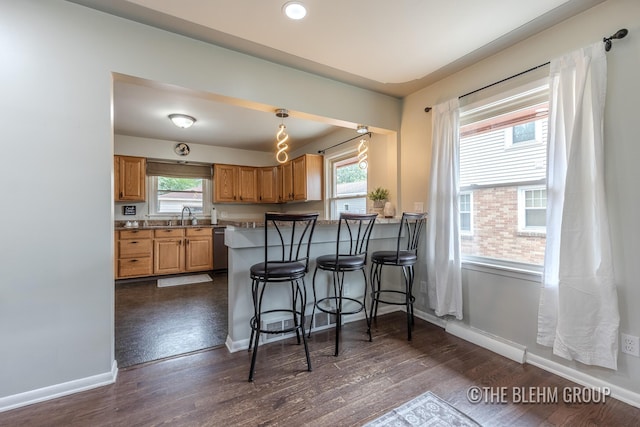 544 Shawmut Blvd NW, Grand Rapids, MI 49504 - kitchen with a breakfast bar area, dark wood-style floors, a peninsula, stainless steel dishwasher, and brown cabinets