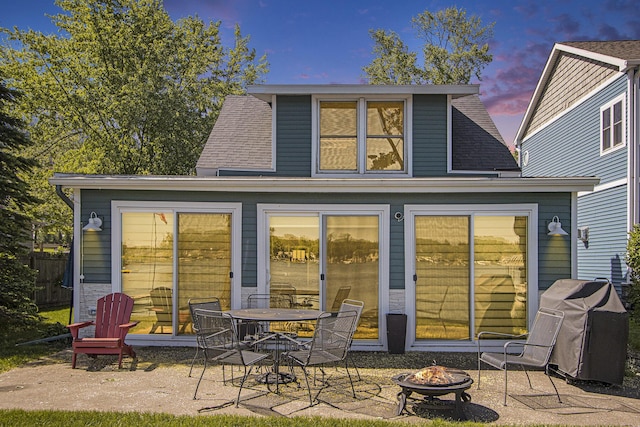 2019 Lakeview Dr, Portage, MI 49002 - back of property at dusk with an outdoor fire pit, a patio, and roof with shingles