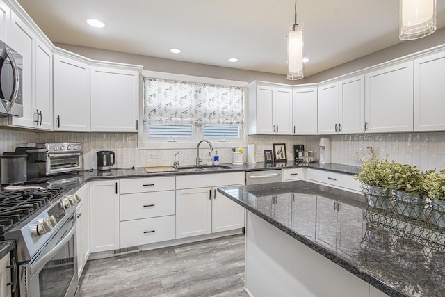 2019 Lakeview Dr, Portage, MI 49002 - kitchen featuring stainless steel appliances, a sink, white cabinetry, light wood-style floors, and pendant lighting