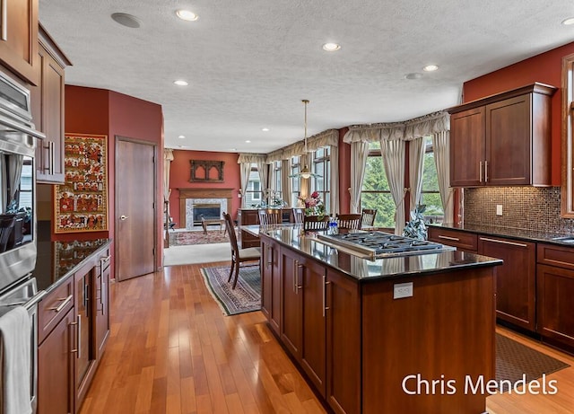 150 Bay Circle Dr, Holland, MI 49424 - kitchen with a textured ceiling, appliances with stainless steel finishes, open floor plan, a fireplace, and a kitchen island