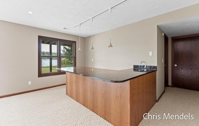 150 Bay Circle Dr, Holland, MI 49424 - kitchen with a peninsula, rail lighting, baseboards, light colored carpet, and a sink