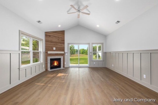 2076 W Lakewood Blvd, Holland, MI 49424 - unfurnished living room featuring a decorative wall, a ceiling fan, wood finished floors, a tiled fireplace, and a wainscoted wall