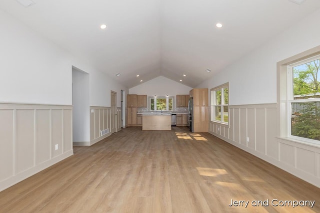 2076 W Lakewood Blvd, Holland, MI 49424 - unfurnished living room with a decorative wall, light wood-style flooring, lofted ceiling, and wainscoting