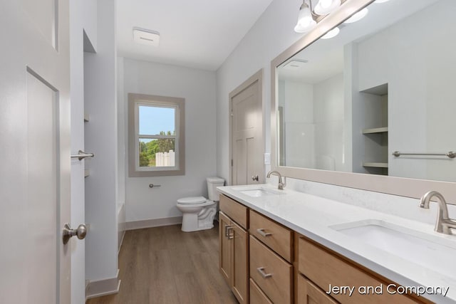 2076 W Lakewood Blvd, Holland, MI 49424 - full bath featuring toilet, double vanity, baseboards, wood finished floors, and a tub to relax in