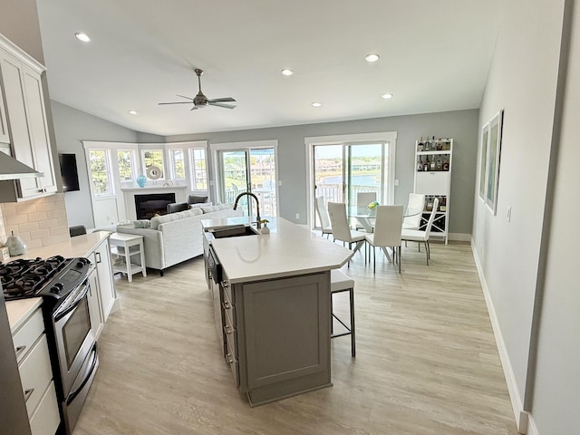 3633 Marina View Pt, Muskegon, MI 49441 - kitchen with a sink, stainless steel gas stove, a glass covered fireplace, plenty of natural light, and recessed lighting