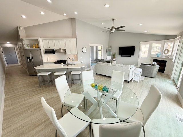 3633 Marina View Pt, Muskegon, MI 49441 - dining room with light wood finished floors, recessed lighting, ceiling fan, a fireplace, and high vaulted ceiling