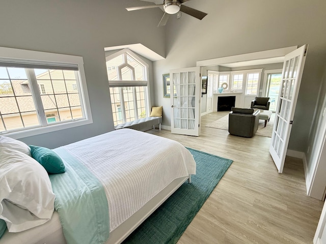 3633 Marina View Pt, Muskegon, MI 49441 - bedroom featuring high vaulted ceiling, light wood-style flooring, baseboards, a fireplace, and french doors