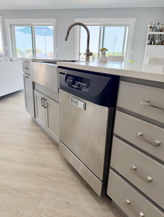 3633 Marina View Pt, Muskegon, MI 49441 - kitchen with dishwasher, light wood-style flooring, light stone counters, a sink, and white cabinetry
