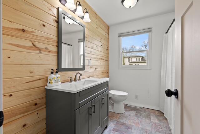 507 E 4th St, Hersey, MI 49639 - full bath with wooden walls, vanity, stone finish flooring, toilet, and baseboards