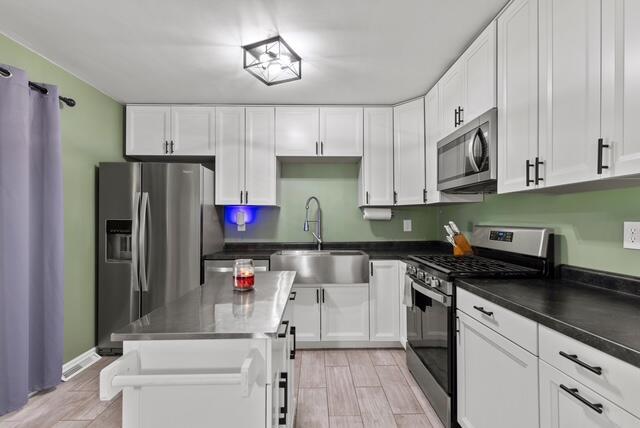 507 E 4th St, Hersey, MI 49639 - kitchen featuring stainless steel appliances, a sink, white cabinetry, and light wood-style floors