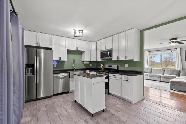 507 E 4th St, Hersey, MI 49639 - kitchen with appliances with stainless steel finishes, dark countertops, light wood finished floors, white cabinets, and ceiling fan