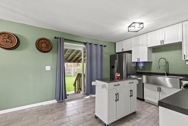 507 E 4th St, Hersey, MI 49639 - kitchen featuring stainless steel appliances, dark countertops, a sink, and light wood-type flooring