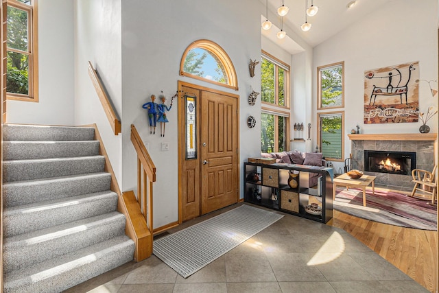 4223 Spring Lake Blvd, Ann Arbor, MI 48108 - foyer entrance featuring high vaulted ceiling, stairs, a tiled fireplace, and tile patterned floors