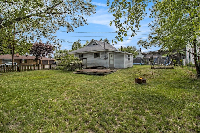 302 Wood St, Hart, MI 49420 - back of house featuring a trampoline, a wooden deck, and an outdoor fire pit