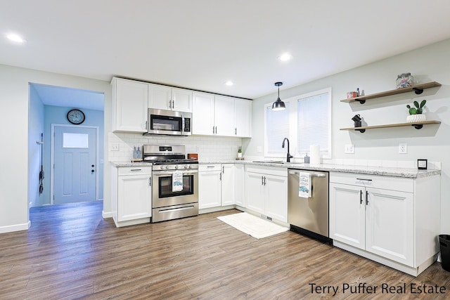 987 Oak Ave, Muskegon, MI 49442 - kitchen with stainless steel appliances, a sink, white cabinets, light wood-type flooring, and recessed lighting