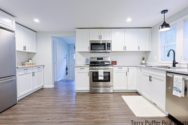 987 Oak Ave, Muskegon, MI 49442 - kitchen featuring appliances with stainless steel finishes, a sink, backsplash, wood finished floors, and white cabinetry