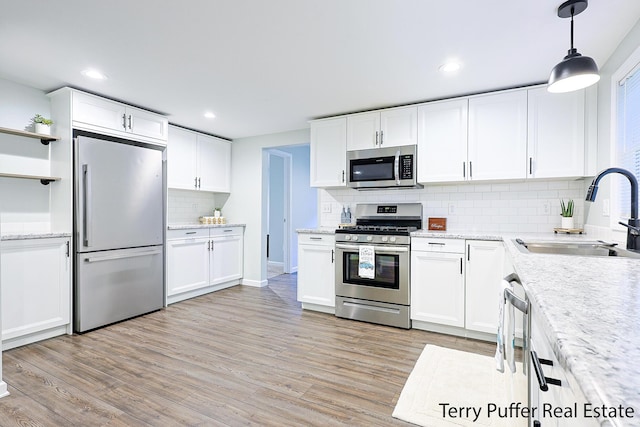 987 Oak Ave, Muskegon, MI 49442 - kitchen featuring stainless steel appliances, a sink, decorative backsplash, white cabinetry, and light wood finished floors