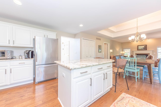 6240 Vineyard Ave, Ann Arbor, MI 48108 - kitchen with freestanding refrigerator, light wood-style flooring, a kitchen island, white cabinets, and decorative light fixtures