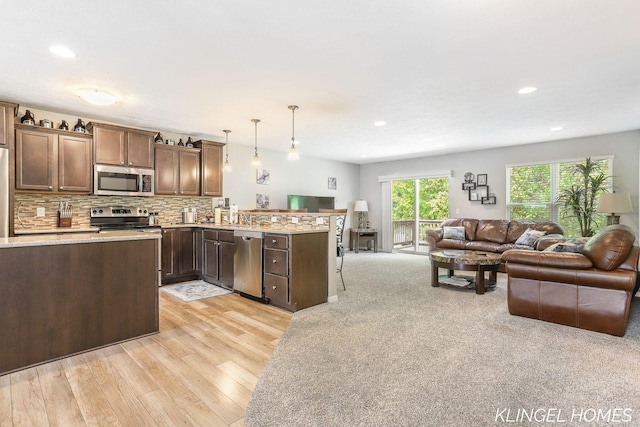 926 N Sandalwood Cir, Muskegon, MI 49441 - kitchen with appliances with stainless steel finishes, open floor plan, a peninsula, light wood-style flooring, and decorative light fixtures