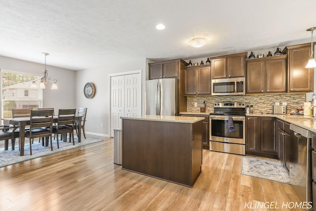 926 N Sandalwood Cir, Muskegon, MI 49441 - kitchen with appliances with stainless steel finishes, a center island, tasteful backsplash, light stone counters, and light wood-style floors