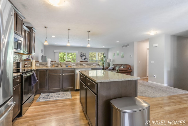 926 N Sandalwood Cir, Muskegon, MI 49441 - kitchen with stainless steel appliances, dark brown cabinetry, open floor plan, light wood-style flooring, and a peninsula