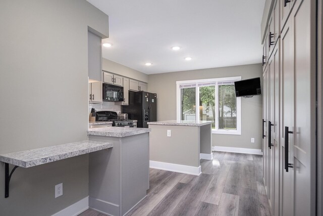 3544 Briggs Blvd NE, Grand Rapids, MI 49525 - kitchen featuring black appliances, light countertops, wood finished floors, baseboards, and a breakfast bar