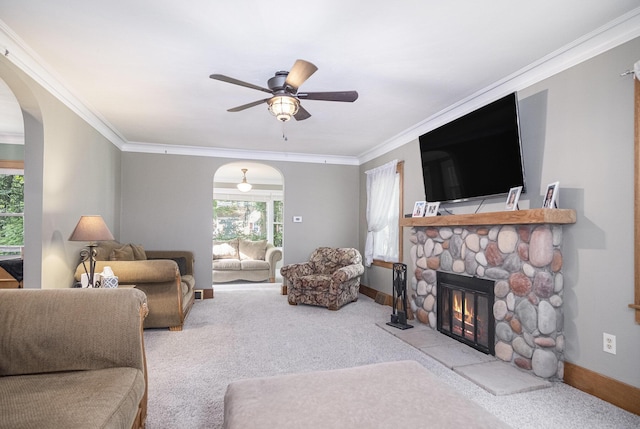 3544 Briggs Blvd NE, Grand Rapids, MI 49525 - carpeted living room featuring arched walkways, a stone fireplace, crown molding, a ceiling fan, and baseboards
