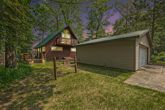 1142 Wolf Lake Dr, Baldwin, MI 49304 - back of property at dusk with an outdoor structure, a balcony, a yard, a wooden deck, and metal roof