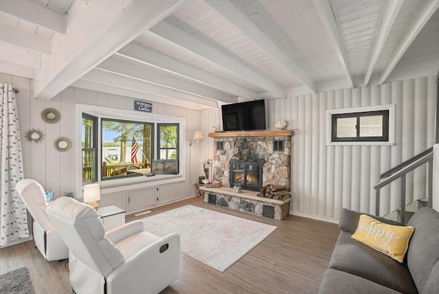1142 Wolf Lake Dr, Baldwin, MI 49304 - living room featuring beam ceiling, wood finished floors, a fireplace, and stairs