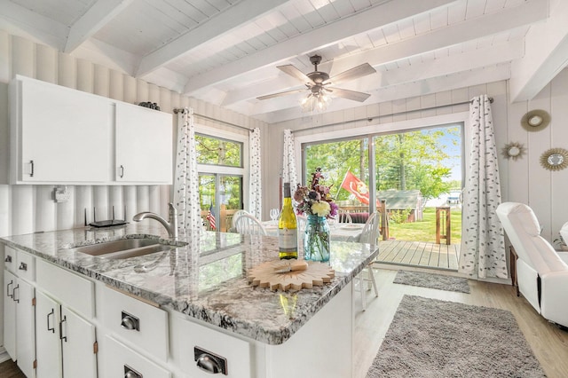 1142 Wolf Lake Dr, Baldwin, MI 49304 - kitchen with a sink, light wood-style flooring, light stone counters, beamed ceiling, and white cabinetry