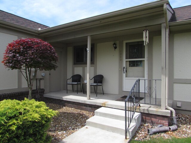 9920 Cambridge Ct, South Lyon, MI 48178 - entrance to property with covered porch, a shingled roof, and stucco siding