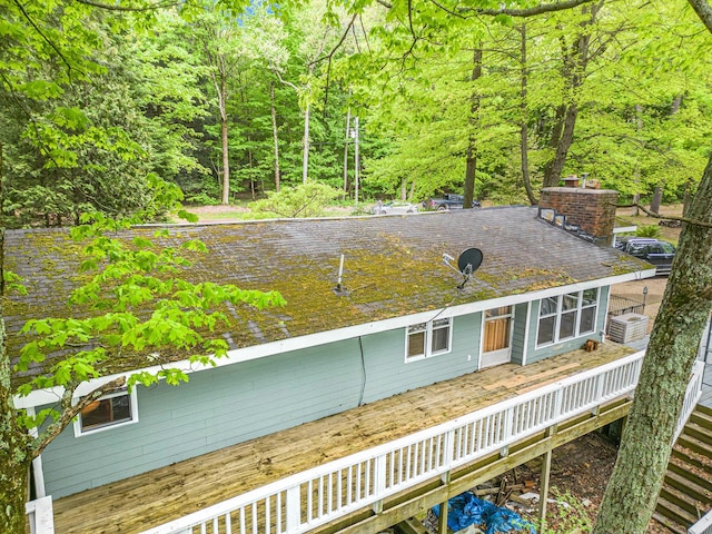 4468 Teal Ln, Newaygo, MI 49337 - rear view of house with a deck, central air condition unit, a chimney, and a wooded view