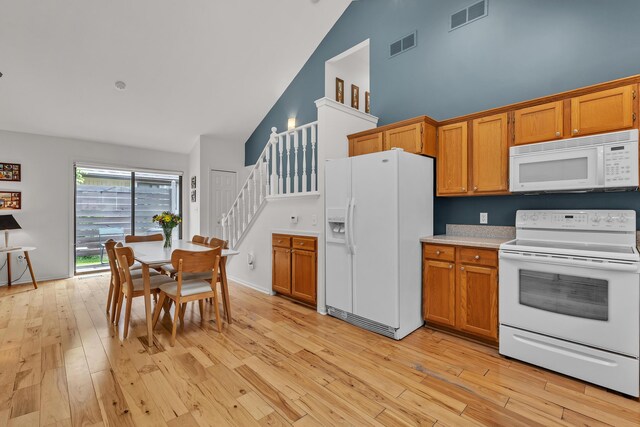 2539 Country Village Ct, Ann Arbor, MI 48103 - kitchen featuring white appliances, high vaulted ceiling, light wood finished floors, light countertops, and brown cabinets