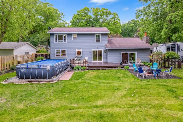 4744 Sandy Ln, Whitehall, MI 49461 - rear view of house with a fire pit, a deck, a chimney, view of scattered trees, and roof with shingles