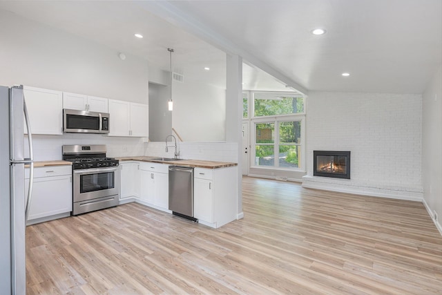 1335 Knapp St NE, Grand Rapids, MI 49505 - kitchen with stainless steel appliances, butcher block counters, open floor plan, a sink, and light wood finished floors