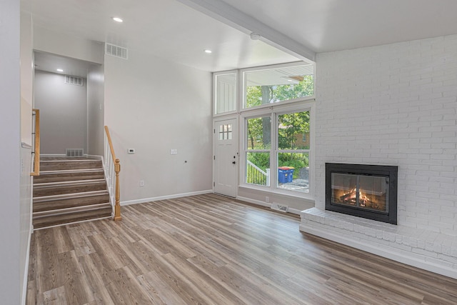1335 Knapp St NE, Grand Rapids, MI 49505 - unfurnished living room with wood finished floors, a fireplace, baseboards, stairway, and recessed lighting