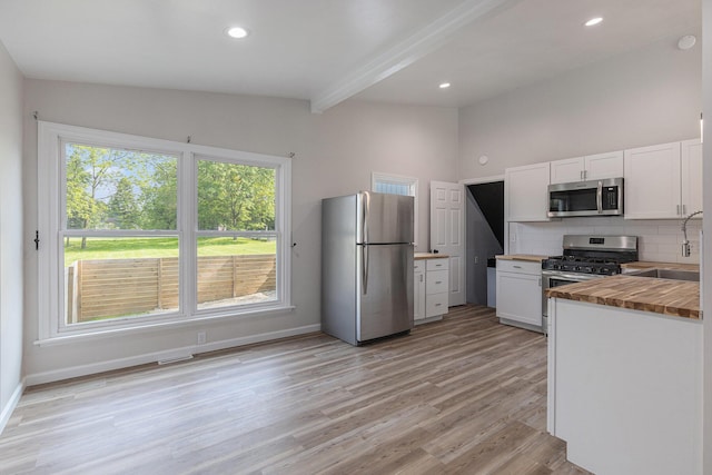 1335 Knapp St NE, Grand Rapids, MI 49505 - kitchen with stainless steel appliances, butcher block countertops, a sink, backsplash, and white cabinets